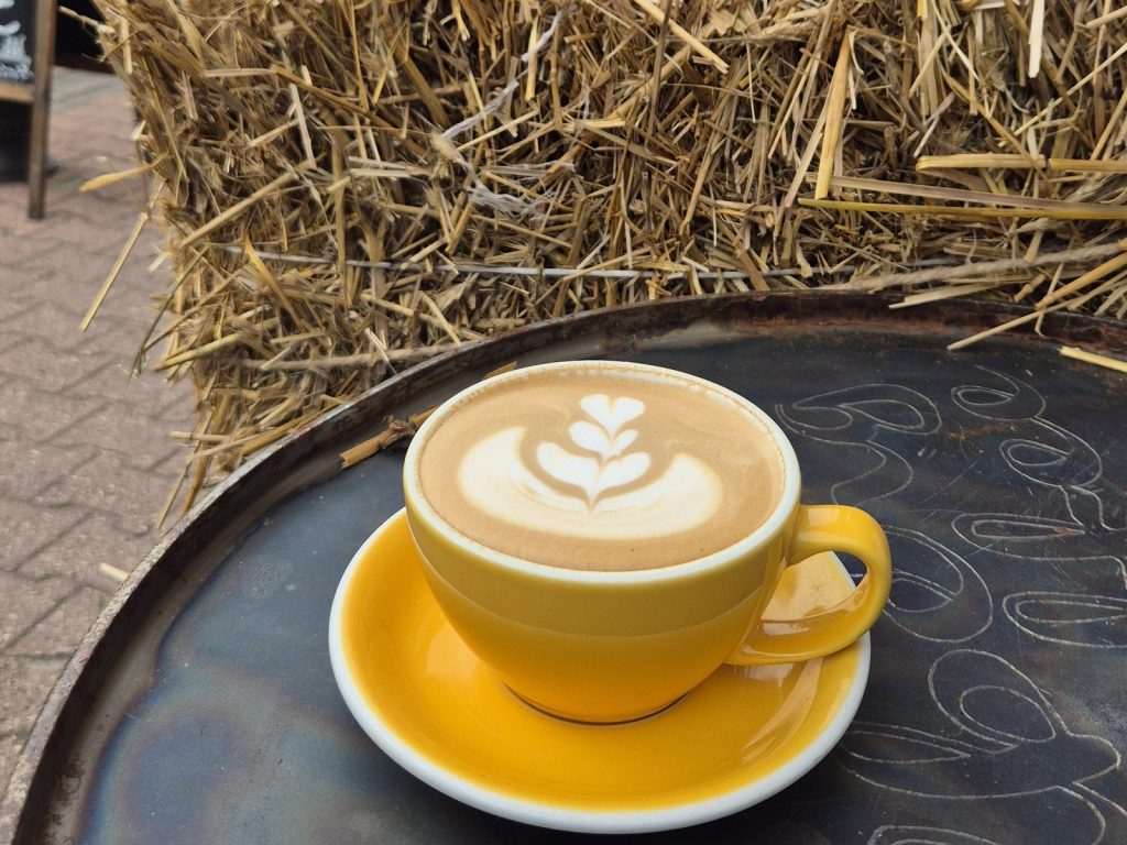 kawa na stoliku w ogródku kawiarni Colbergcoffee jesienią, w tle snopek siana